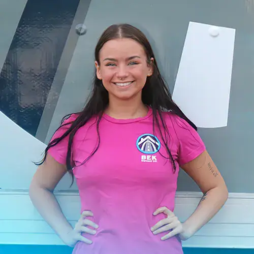 Lea+Conway+BEK-Crew Smiling person in pink shirt by company logo.