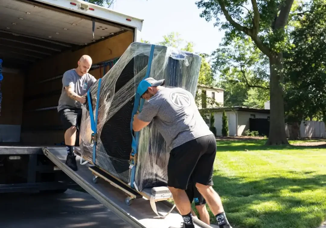 The-New-Standard-in-Moving Two movers unloading furniture from a truck.