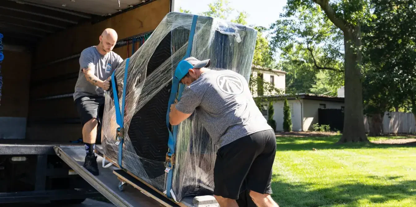 Two movers unloading furniture from a truck.