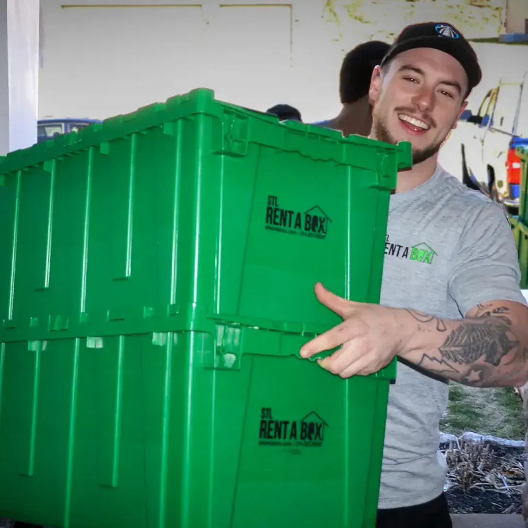 man carrying green moving boxes to doorway